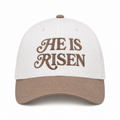 He Is Risen Baseball Cap in Ash Mocha front view showing cream cotton crown with mocha decorative script He Is Risen embroidery, mocha bill, and mocha top button on white background
