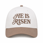 He Is Risen Baseball Cap in Ash Mocha front view showing cream cotton crown with mocha decorative script He Is Risen embroidery, mocha bill, and mocha top button on white background
