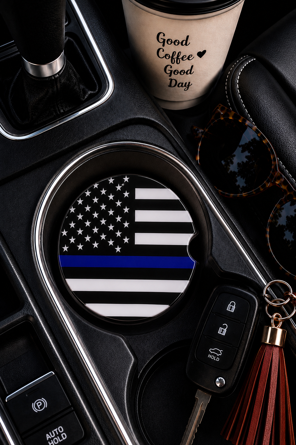 Thin Blue Line ceramic car coaster in cup holder — black and white American flag with thin blue line design, shown in car console with coffee cup and sunglasses
