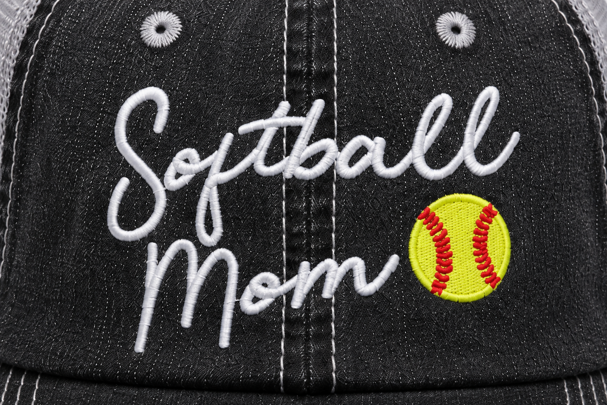 Close-up of embroidered "Softball Mom" script and softball graphic on a distressed black trucker hat front panel.
