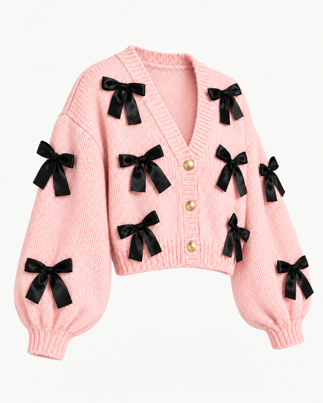 Angled view of the pink knit cardigan showing black bows across the front and sleeves, dropped shoulders, ribbed cuffs, and cropped hem
