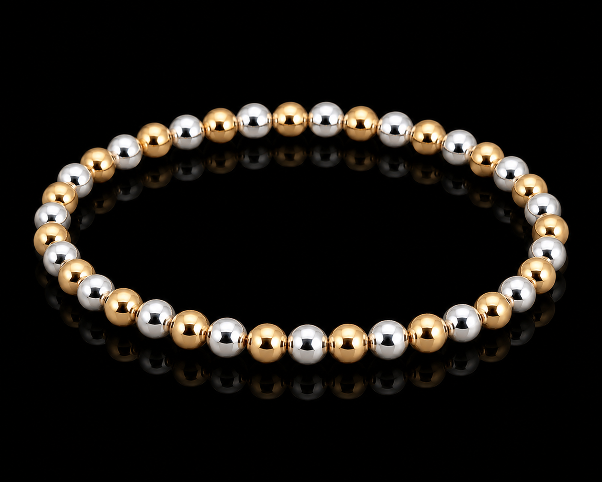 Gold and silver alternating round bead stretch bracelet shown at an angle on black reflective surface
