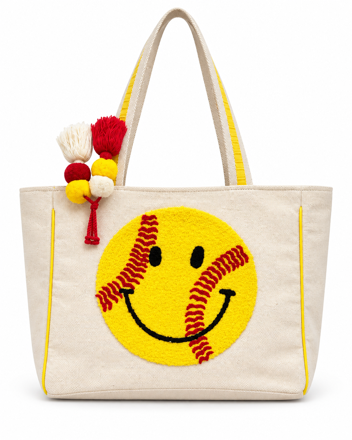 Softball Smiley Tote Bag front view with natural canvas body, large yellow textured softball smiley face with red stitching, yellow trim, and red yellow and cream pom-pom tassel accent on white background
