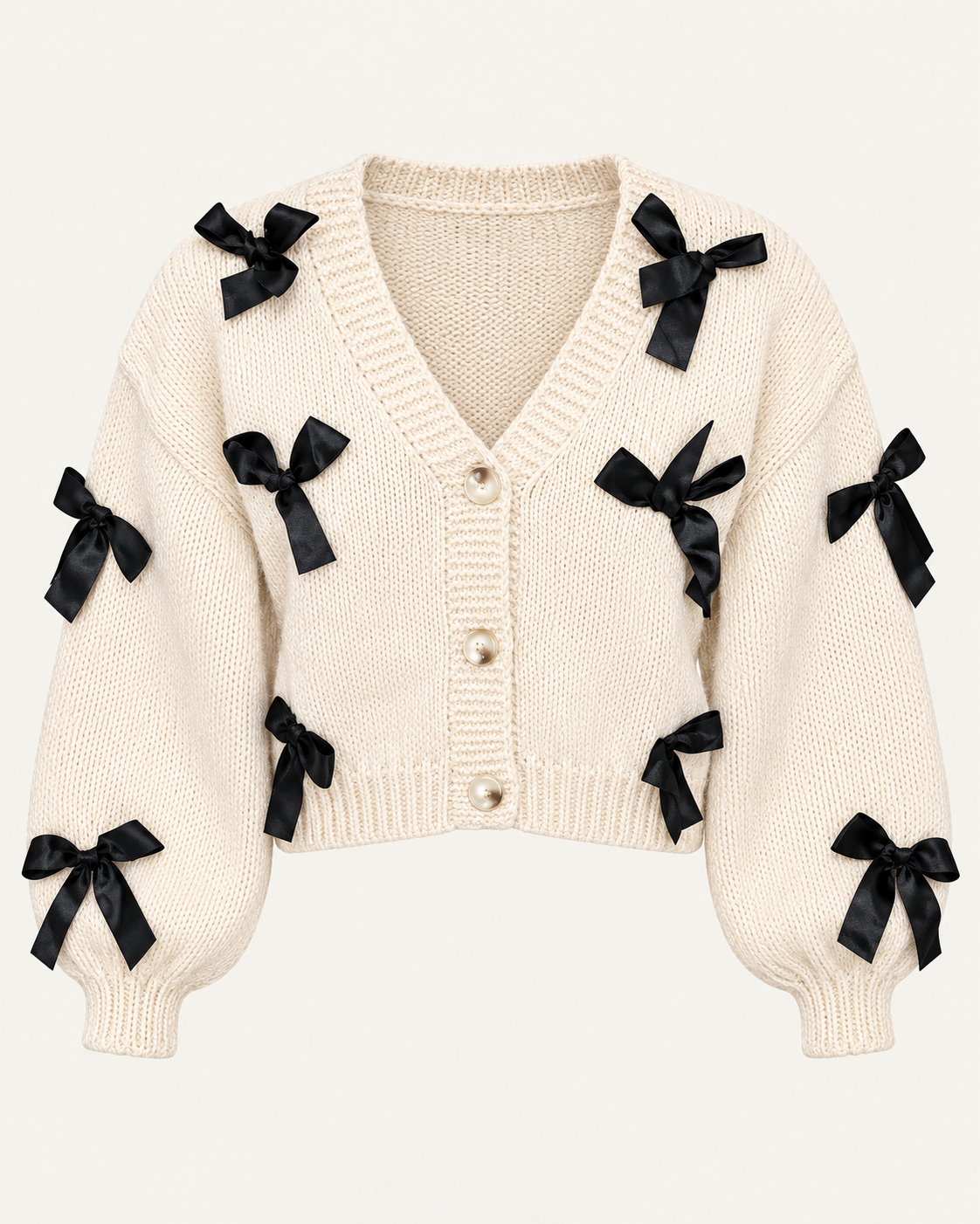 Front view of the tan cropped cardigan showing black ribbon bows, a ribbed V-neckline, three front buttons, and long sleeves
