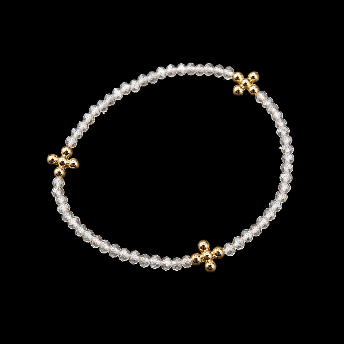 Clear faceted beaded stretch bracelet with gold cross accents shown at an angle on black reflective surface
