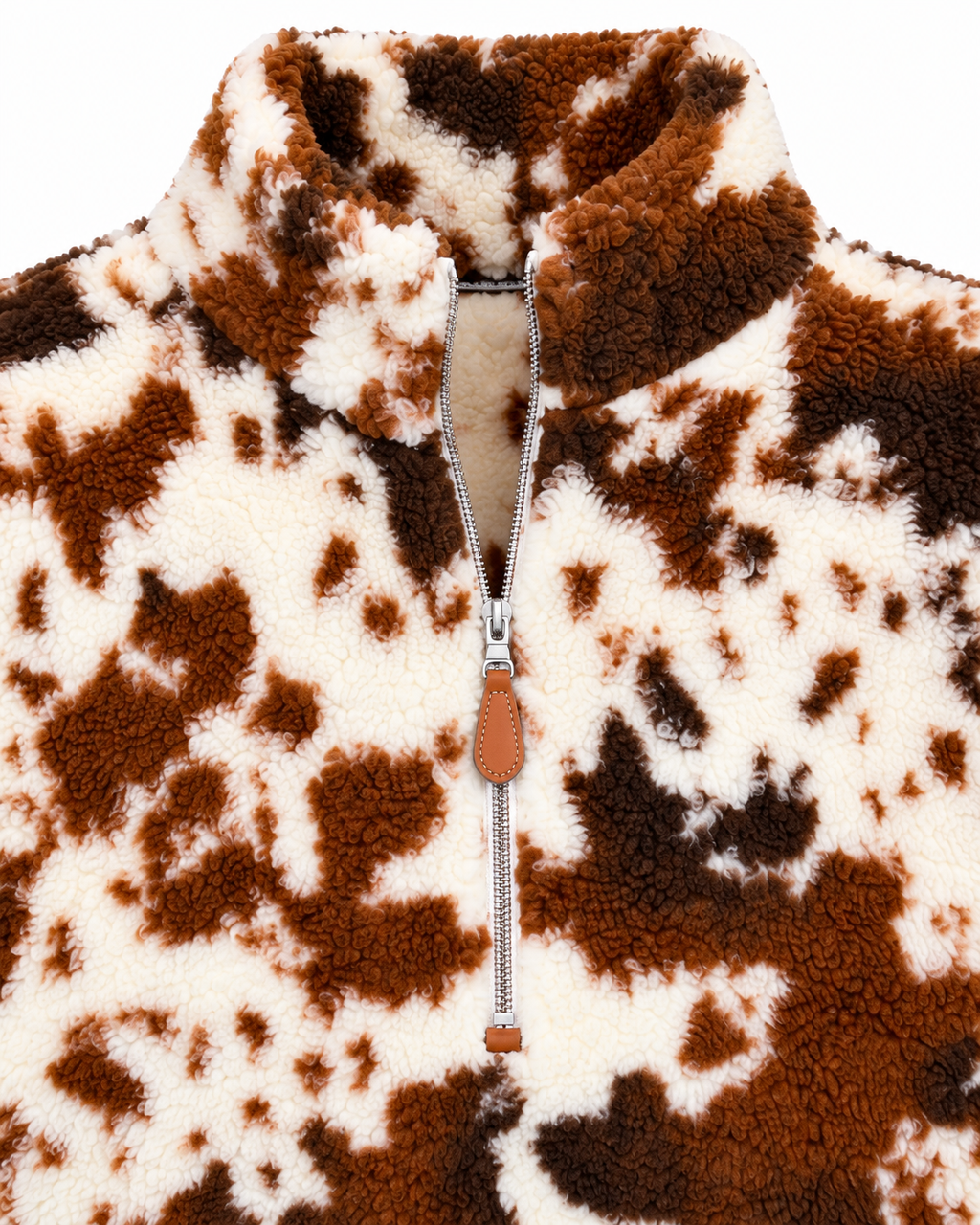 Close-up of the cow print sherpa pullover showing its stand collar, silver-tone quarter zipper, brown pull tab, and plush texture
