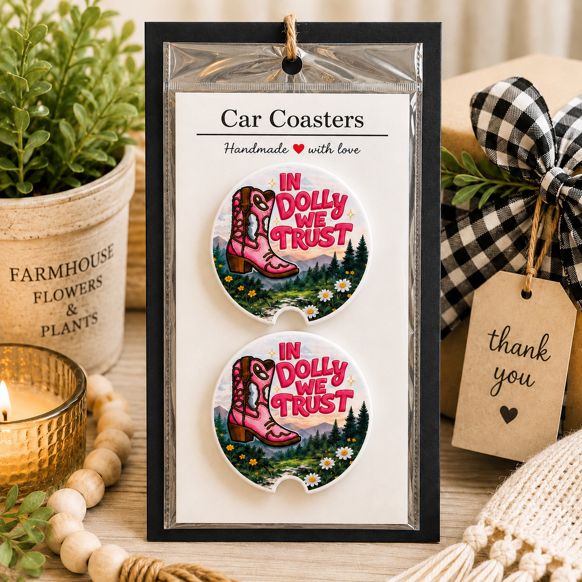 In Dolly We Trust Car Coaster Set in handmade packaging — gift-ready ceramic coasters with pink cowgirl boot and mountain meadow scene, set of 2
