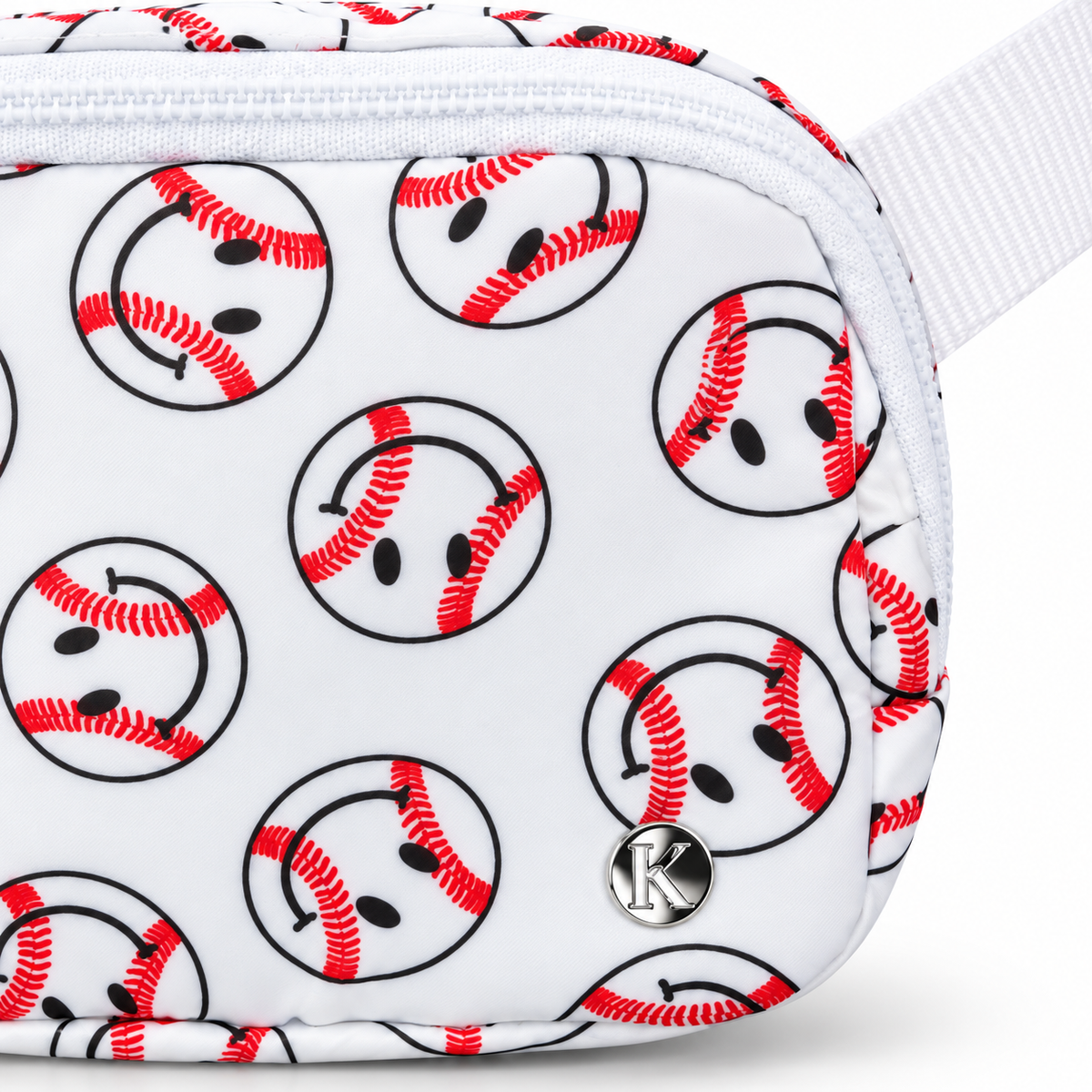 Close-up of Baseball Smiley Belt Bag showing white nylon with allover baseball smiley face print featuring red curved stitching and black dot eyes and smile in black circles, silver Katydid K logo rivet, and white top zipper edge
