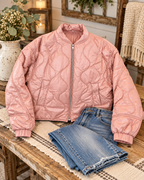 Blush pink quilted full-zip jacket styled with distressed jeans, a fringed runner, flowers, greenery, and lanterns
