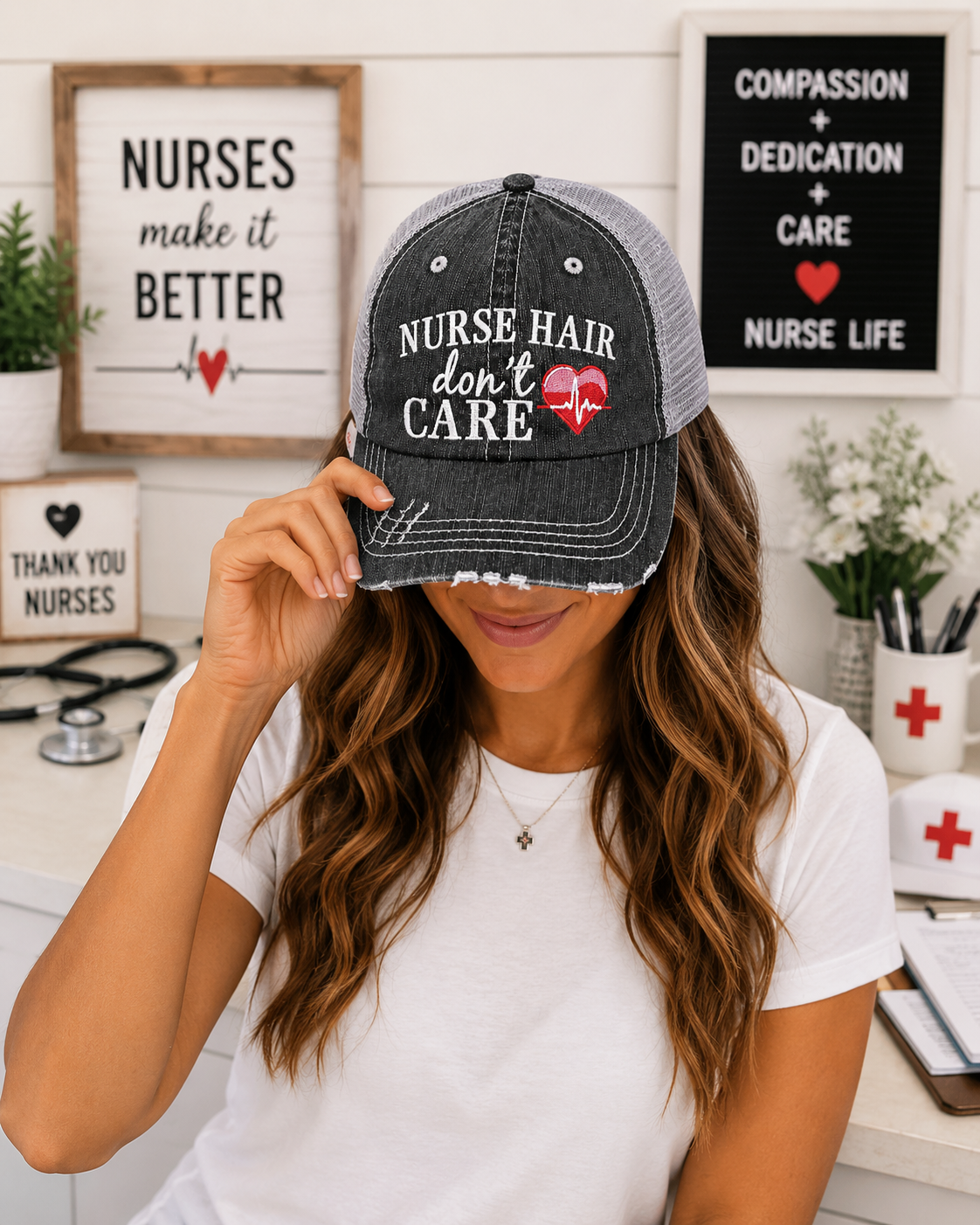 A woman wearing a gray and black trucker-style baseball cap with the text 'NURSE HAIR don't CARE' and a red heart graphic, holding the brim over her eyes in a brightly lit nurse-themed room.