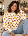 Seated model wearing a cream sweatshirt with yellow smiley faces in pink cowgirl hats and blue jeans
