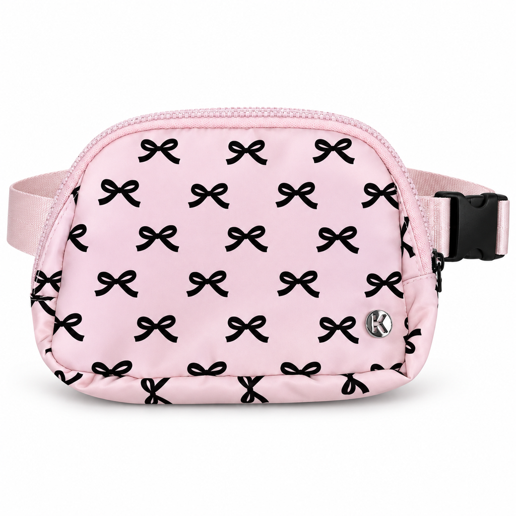 Pink Bow Belt Bag and Crossbody front view showing pink nylon with all-over black bow print, top zipper main compartment, silver Katydid K logo rivet, and adjustable pink satin strap with black side-release buckle on white background

