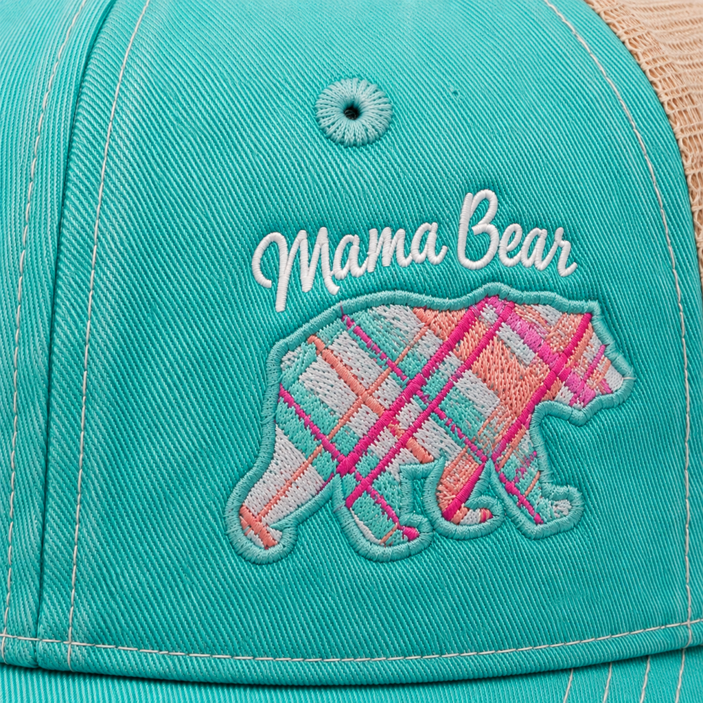 Close-up of Mama Bear script embroidery above colorful plaid bear patch on distressed aqua trucker hat
