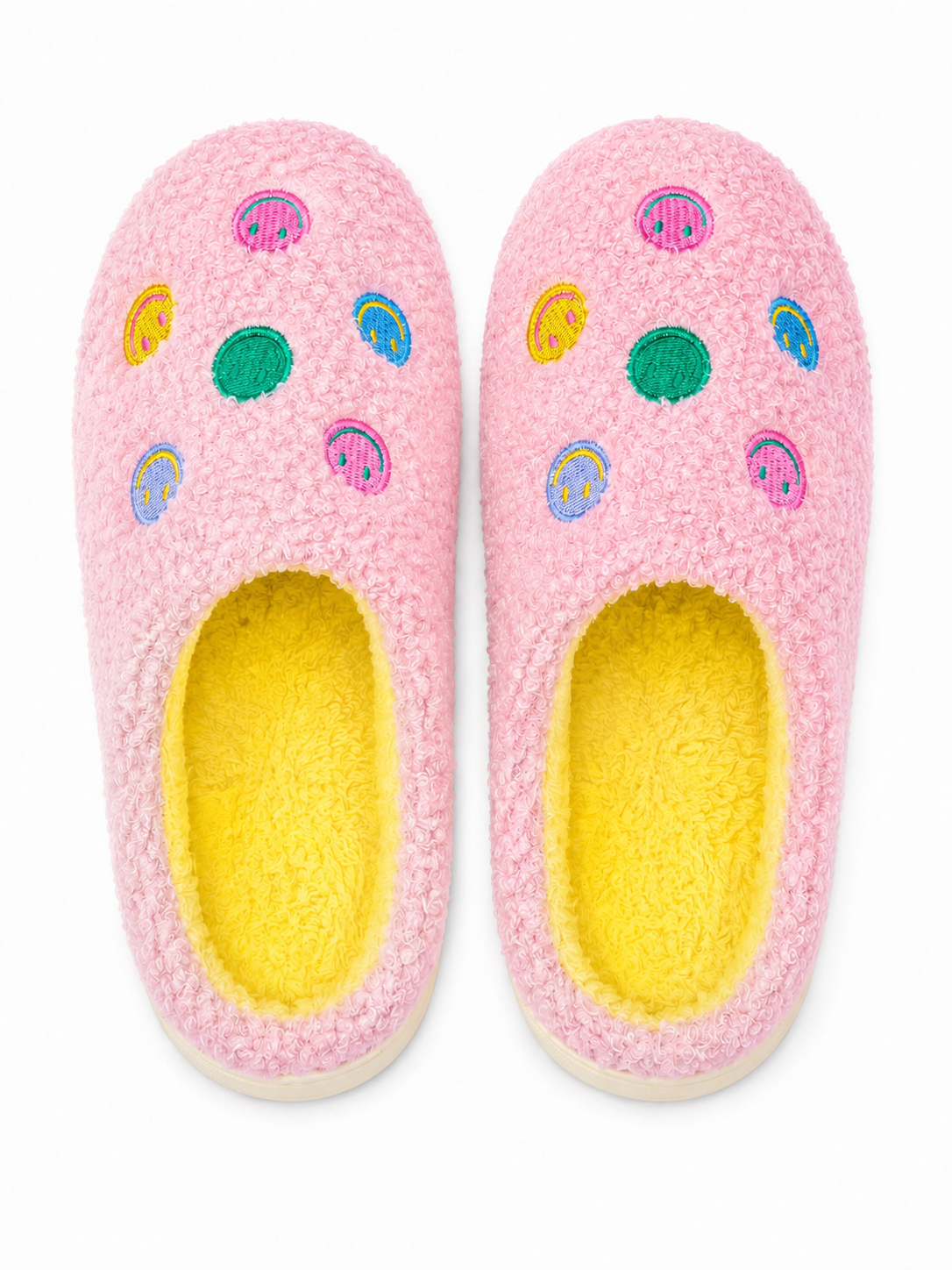 Pink Smiley Face Fuzzy Slippers flat lay showing colorful embroidered smiley face accents on pink fuzzy exterior with bright yellow interior lining