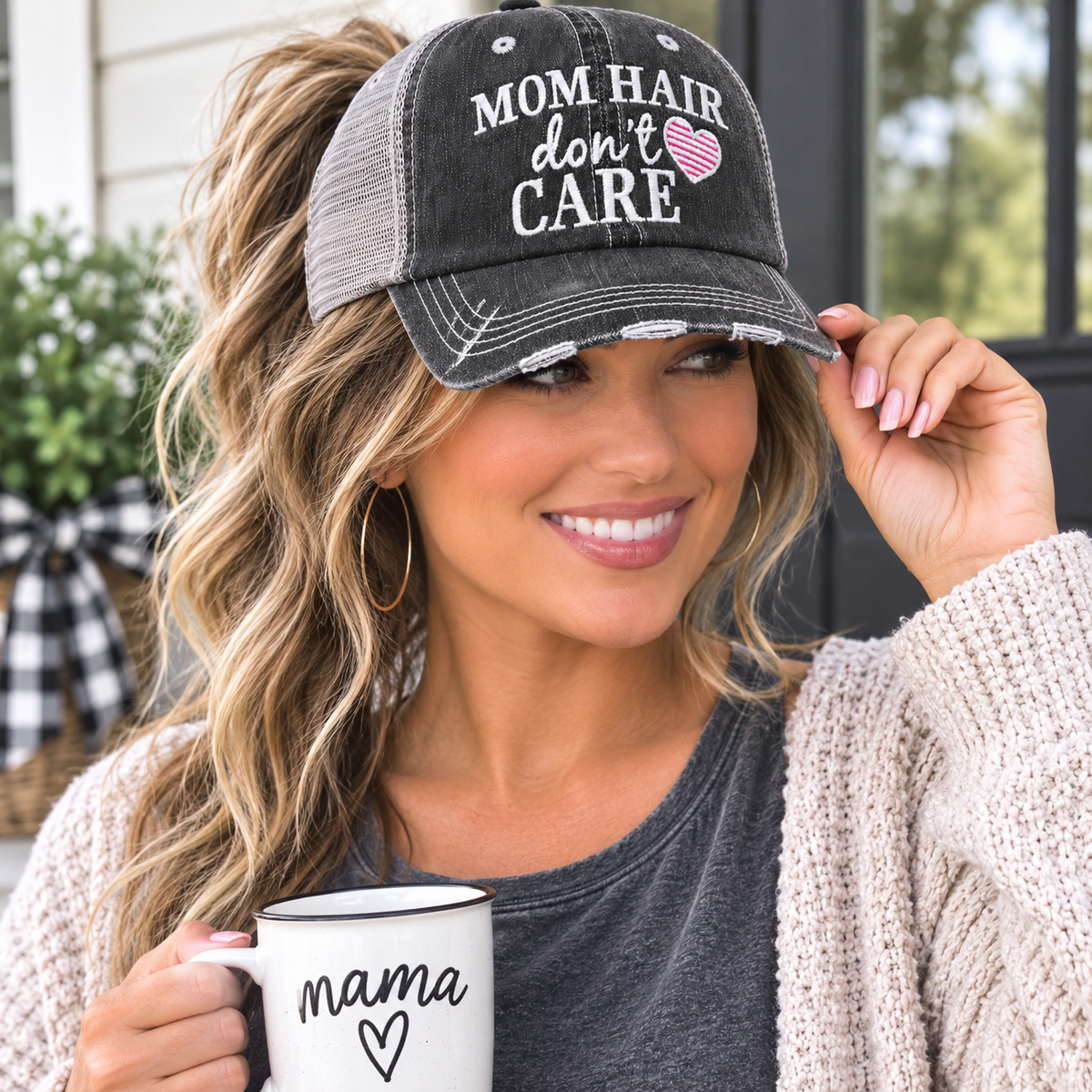 Woman wearing Mom Hair Don't Care distressed charcoal trucker hat with pink striped heart embroidery
