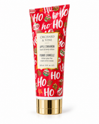 Angled view of the Apple Cinnamon lotion tube showing red Christmas packaging, white HO HO HO lettering, and a gold-tone cap
