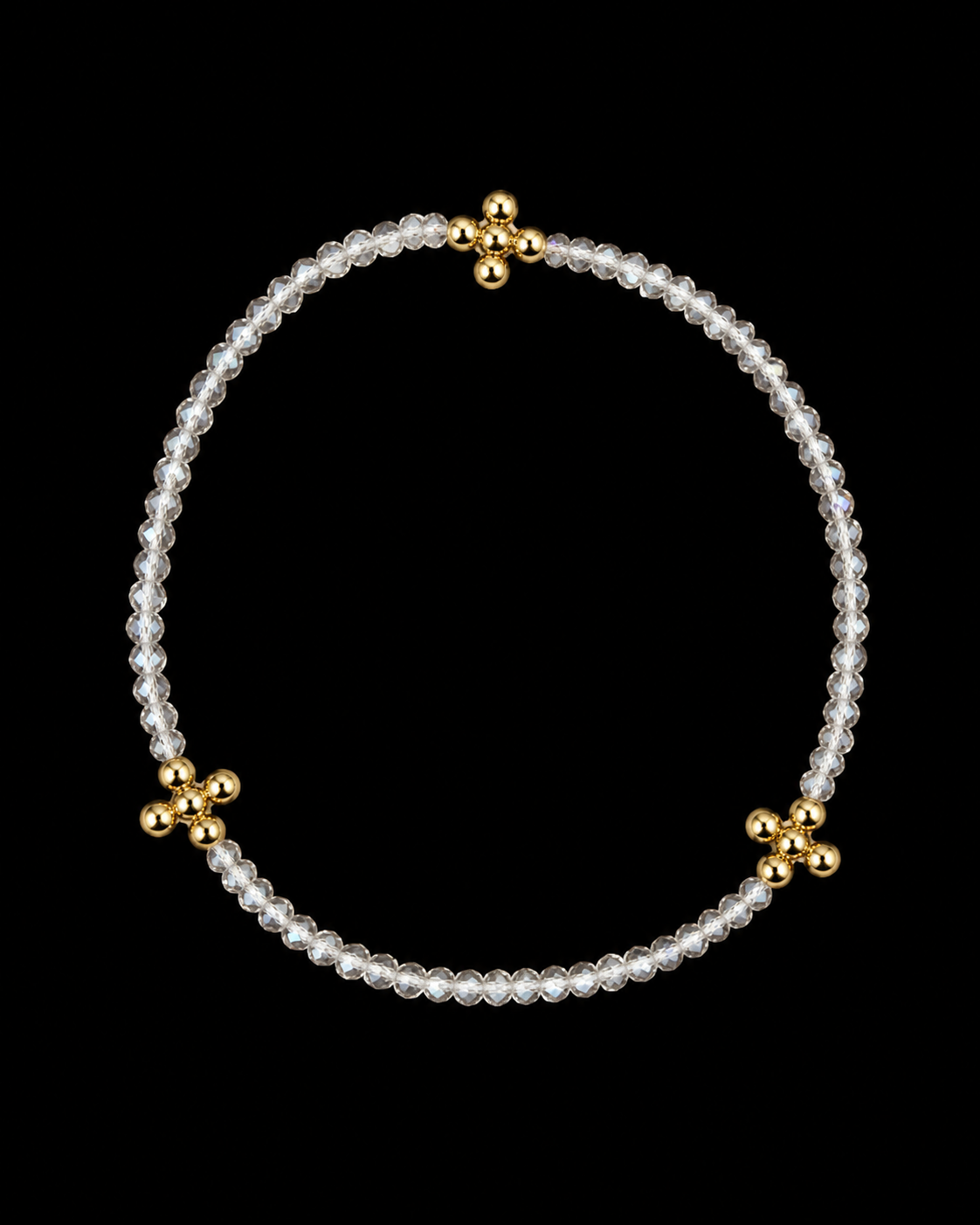 Clear faceted beaded stretch bracelet with three gold cross-shaped bead accents displayed flat in a circle on black background
