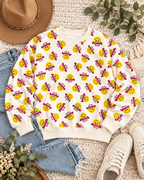 Cowgirl smiley face sweatshirt styled with blue jeans, white sneakers, a tan hat, and greenery on a cream textured background
