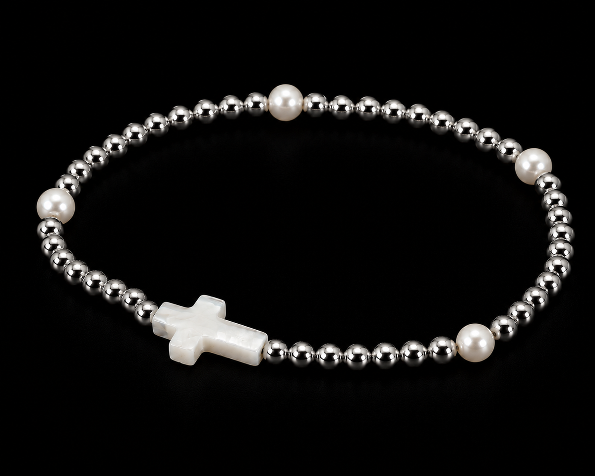 Silver beaded cross bracelet with pearl accents shown at an angle on black reflective surface
