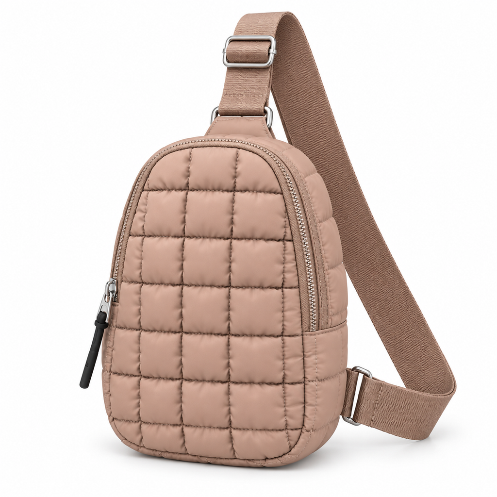 Taupe Quilted Sling Bag three-quarter angle view showing soft taupe puffer nylon with grid square quilted pattern, diagonal main zipper closure with silver hardware, exterior front zippered pocket, and adjustable taupe woven strap with silver buckle hardware on white background
