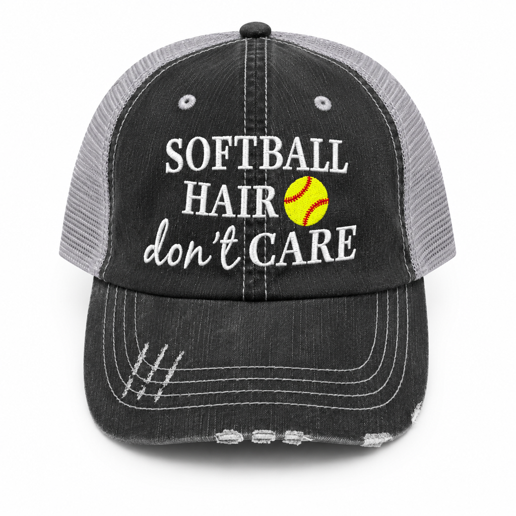 A distressed trucker-style baseball cap with a black washed front panel and brim, gray mesh back, and white embroidered text reading 'SOFTBALL HAIR don't CARE' alongside a yellow softball graphic.