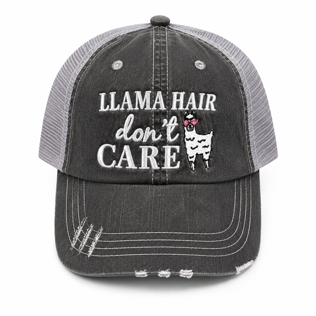 A distressed trucker-style baseball cap with a washed charcoal gray front panel and brim, light gray mesh back, and white embroidered text reading 'LLAMA HAIR don't CARE' with a llama wearing pink heart-shaped sunglasses.