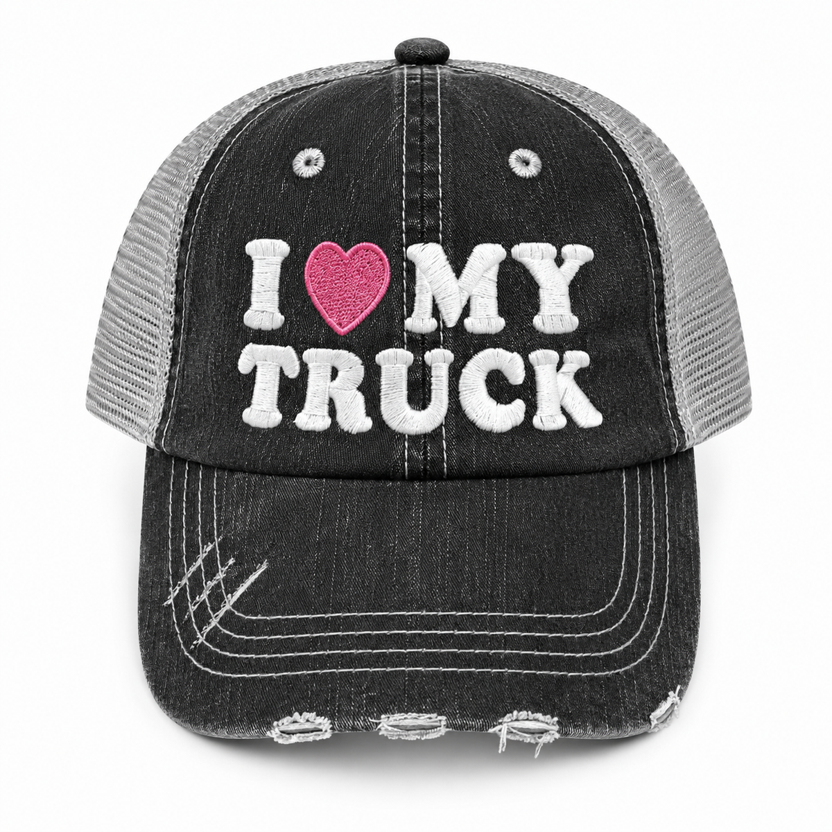 A distressed trucker hat with a black washed denim-look front panel and brim, gray mesh back, and white embroidered text reading 'I [pink heart] MY TRUCK' on the front.