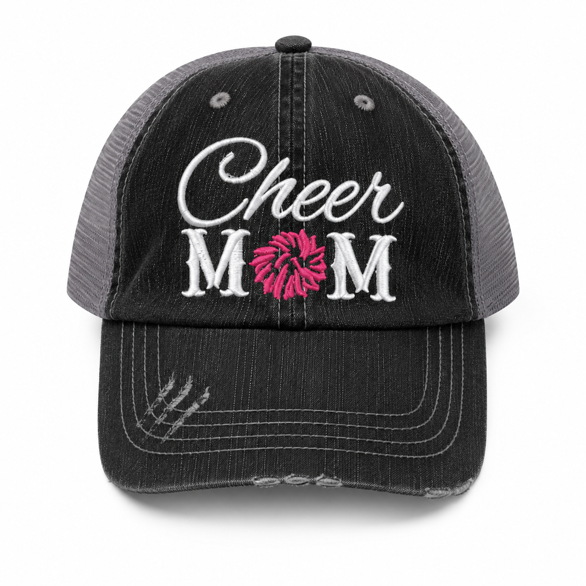 Cheer Mom trucker hat in distressed black denim front with white script embroidery and pink pom-pom detail, shown on a white background.
