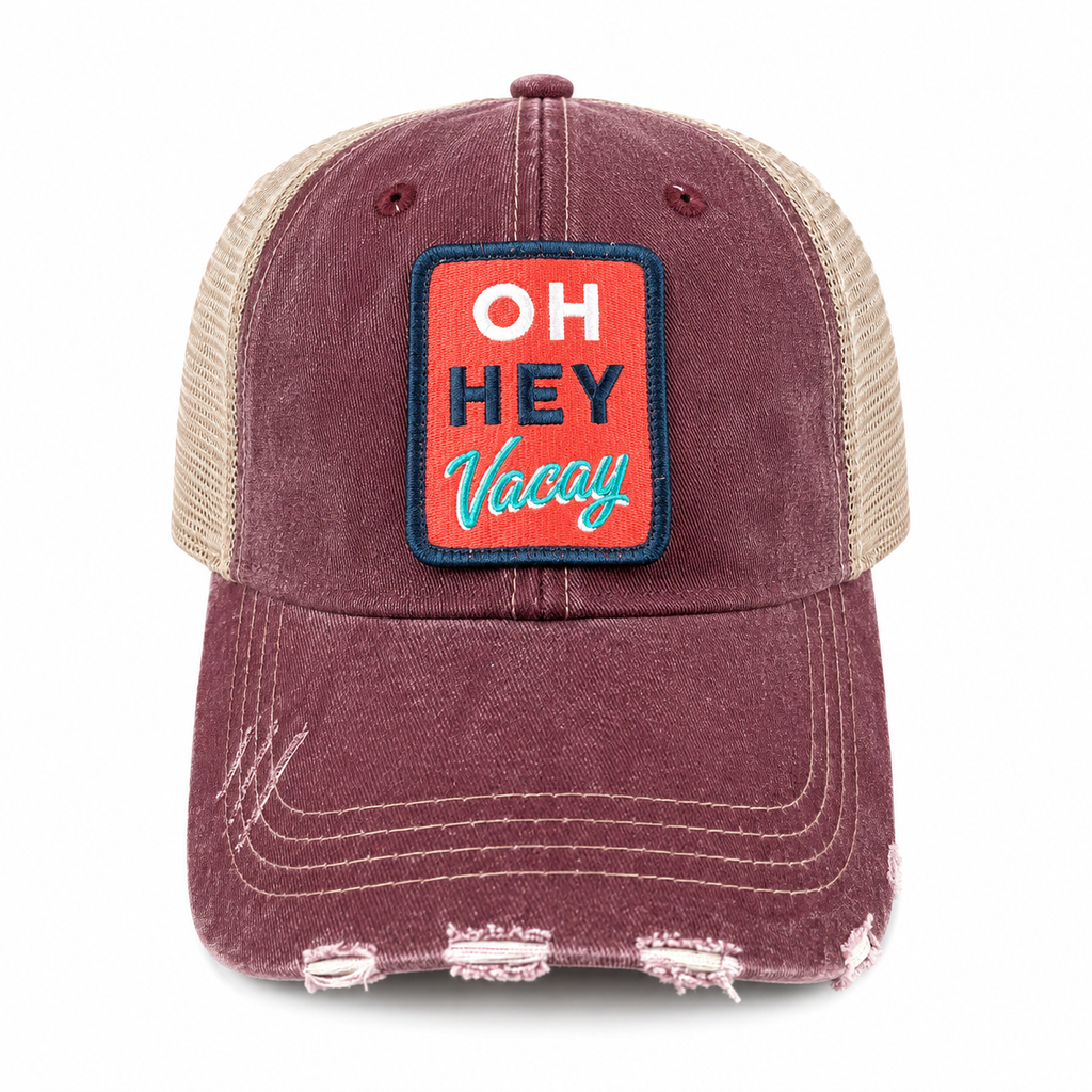 Distressed burgundy trucker hat with tan mesh back and retro Oh Hey Vacay embroidered patch, shown at an angle on a white background.