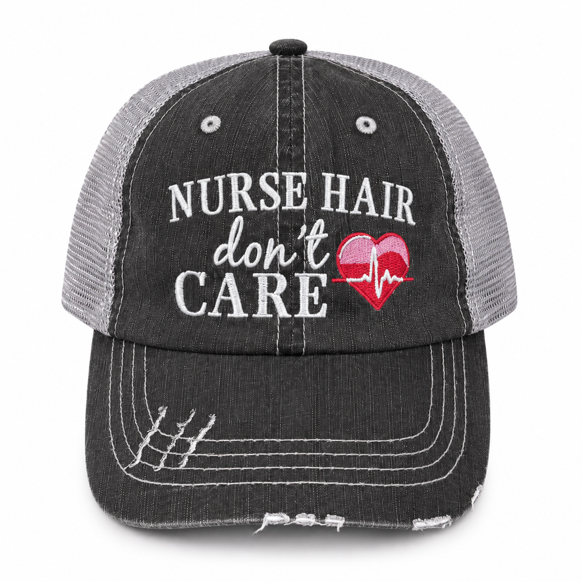 A distressed trucker-style baseball cap with a dark gray washed front panel and brim, and light gray mesh back panels. The front features white embroidered text reading 'NURSE HAIR don't CARE' alongside a red heart with a white EKG line.