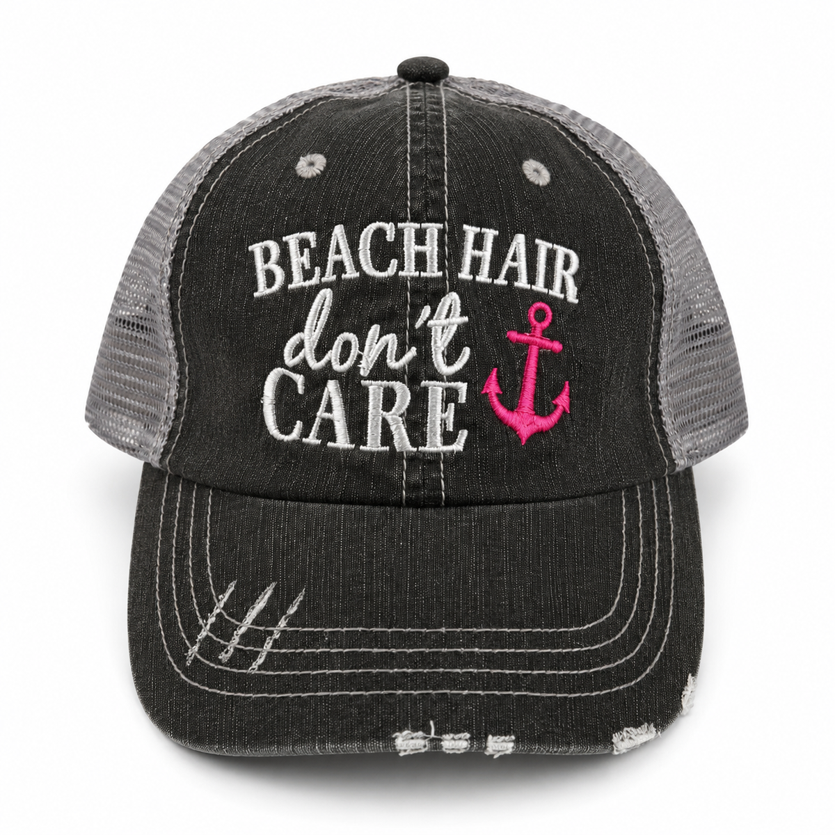 A distressed trucker hat with a washed black front panel and brim, gray mesh back panels, and white embroidered text reading 'BEACH HAIR don't CARE' alongside a pink anchor graphic.