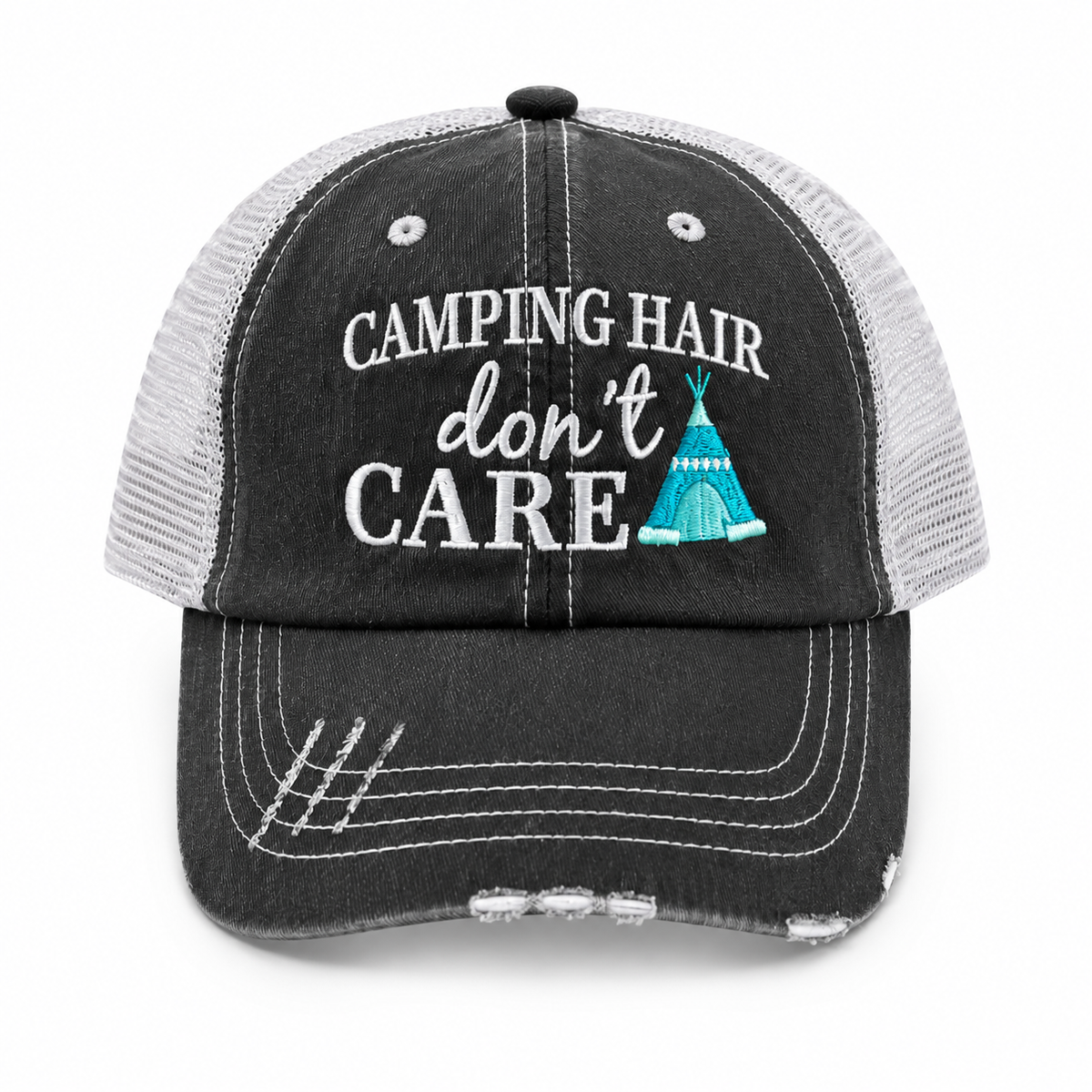 A distressed trucker hat with a washed black front panel and brim, and a light gray mesh back. The front features white embroidered text reading 'CAMPING HAIR don't CARE' alongside a small turquoise teepee graphic.
