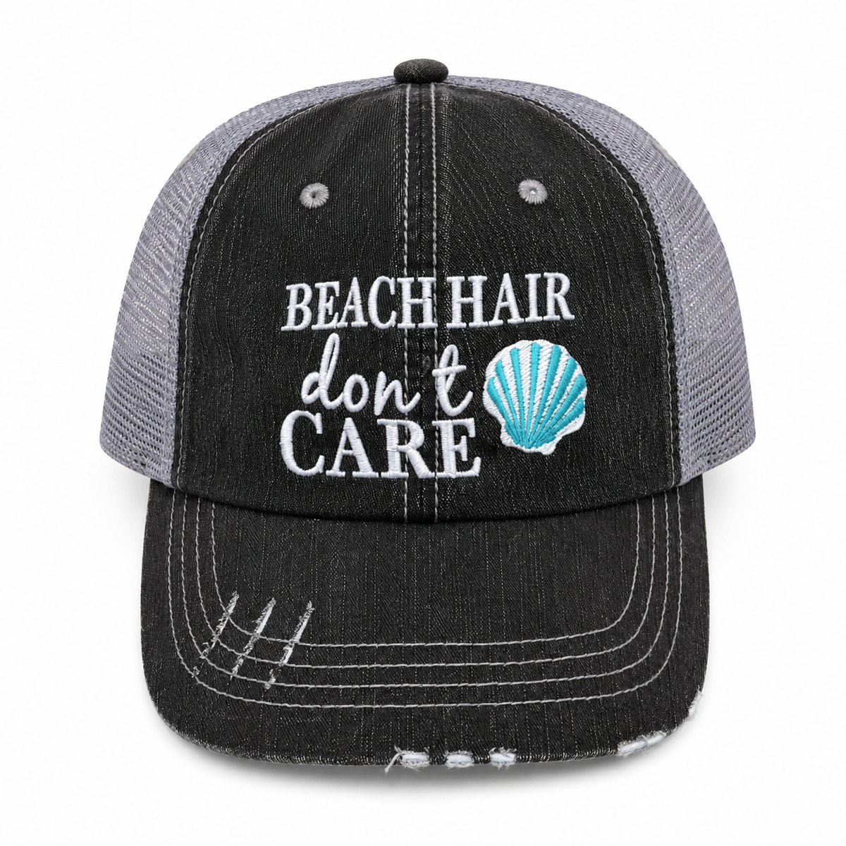 Beach Hair Don't Care trucker hat in distressed black denim front with white embroidery and teal seashell detail, shown on a white background.

