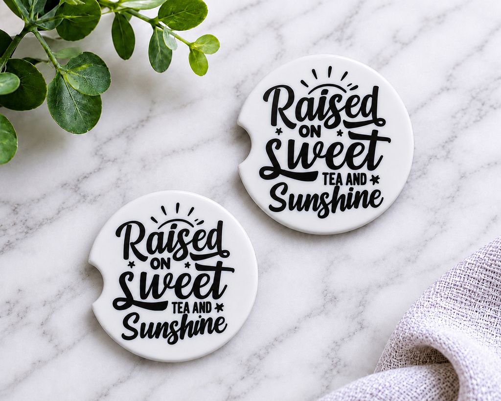 Raised on Sweet Tea and Sunshine car coasters with bold black script on white background