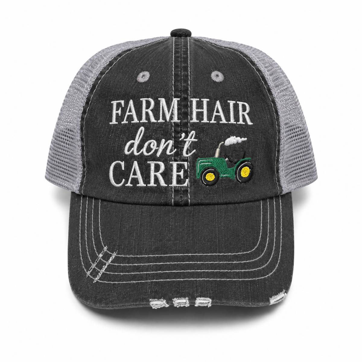 Farm Hair Don't Care trucker hat in distressed black denim front with white embroidered lettering and green tractor detail, shown on a white background.
