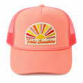 A coral pink trucker hat with a mesh back and a front patch featuring a colorful sunburst and the embroidered text 'Hello Sunshine'.